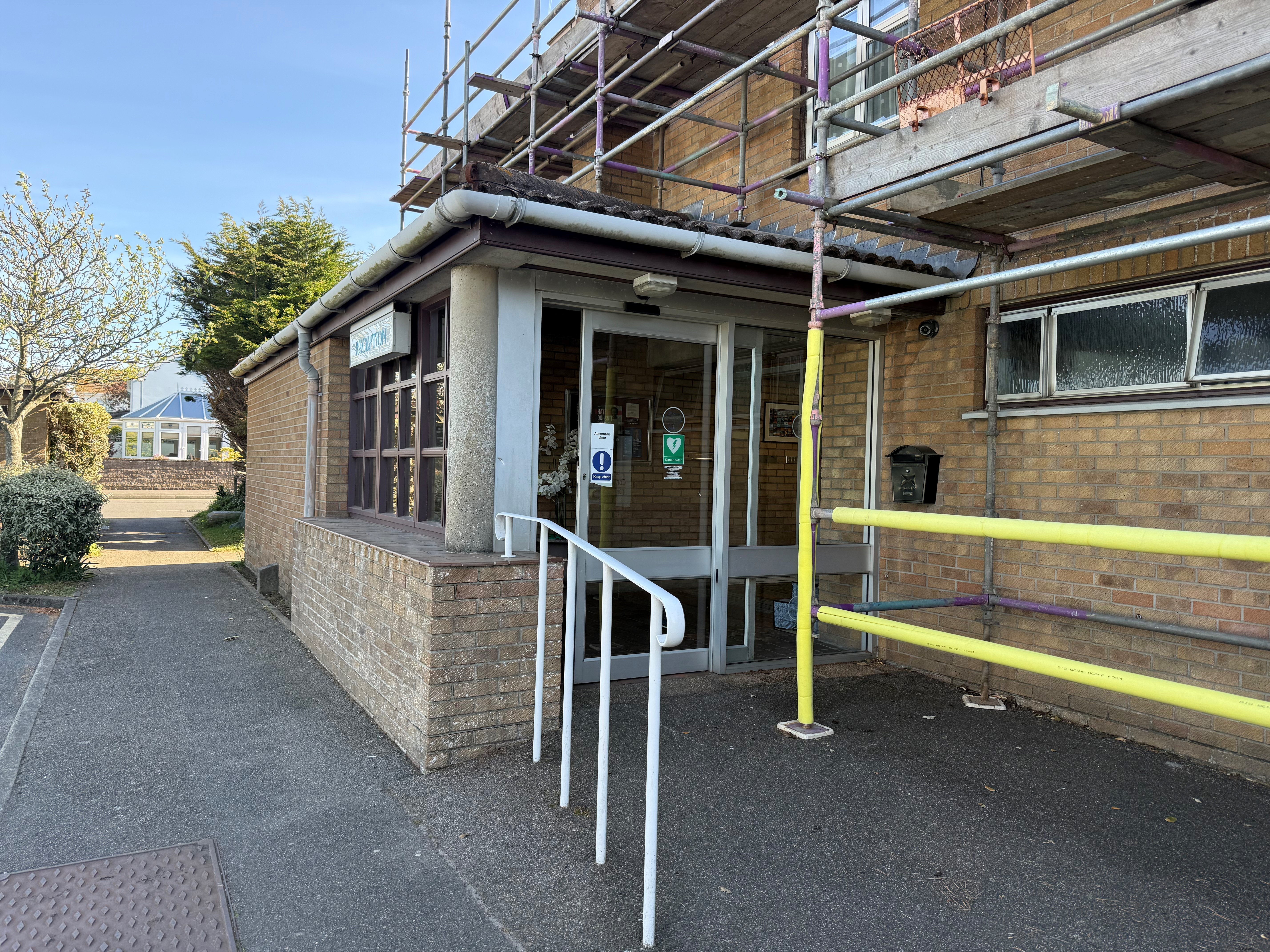 Doors leading into main entrance of the Communicare Centre with handrail. Scaffolding is close to doorway