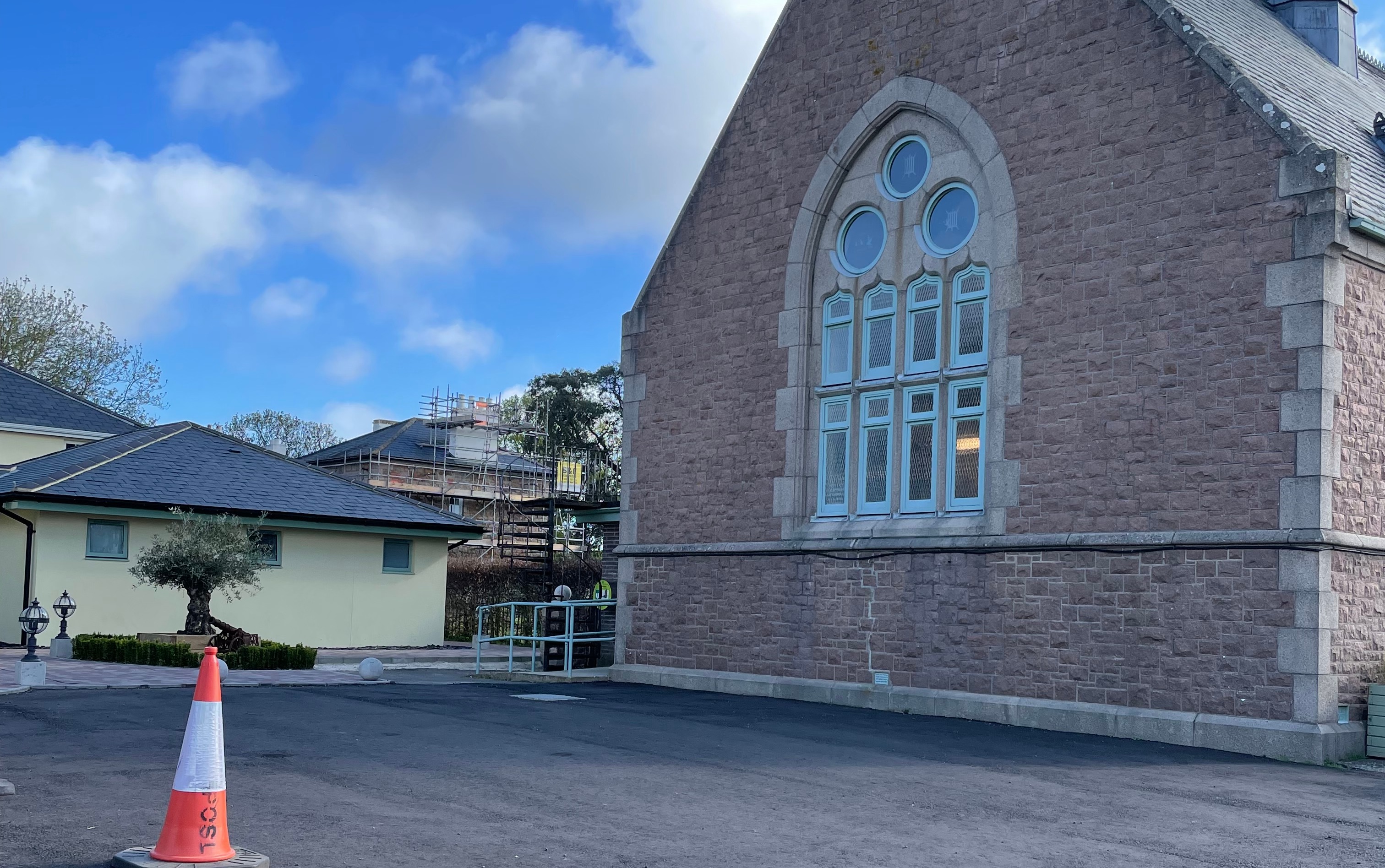 Parking area beside the Parish Hall under arched blue-framed windows