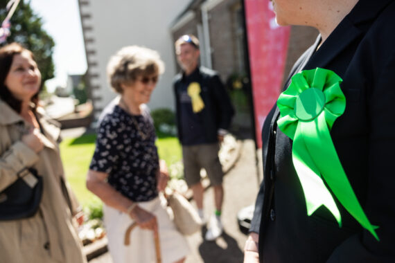 Two candidates outside a polling station welcoming voters